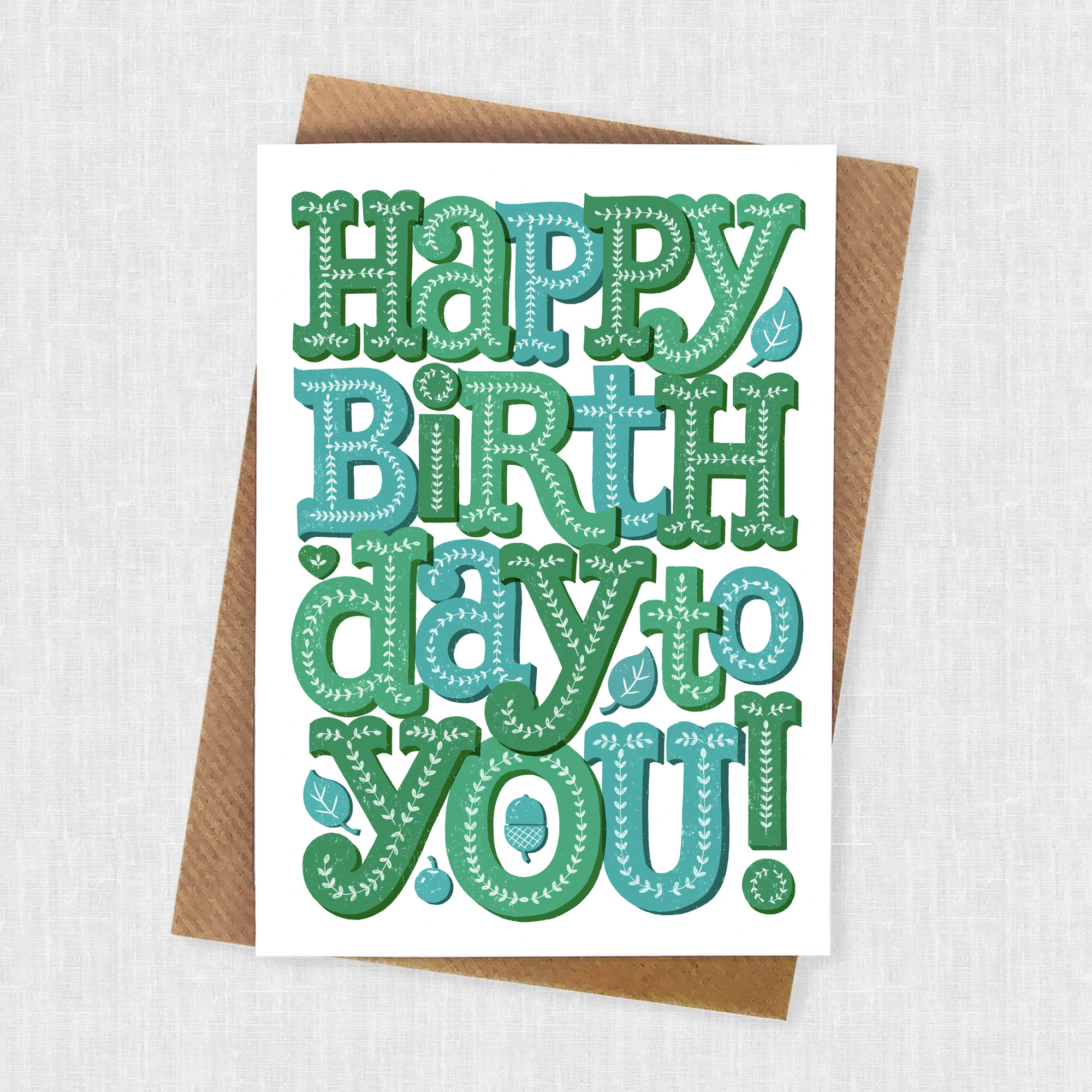Green hand lettered birthday card with leaf decoration in shades of green.